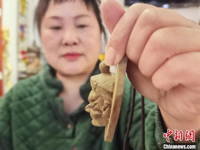 圖為楊云霞制作的儺面具吊墜?！≈苎嗔?攝