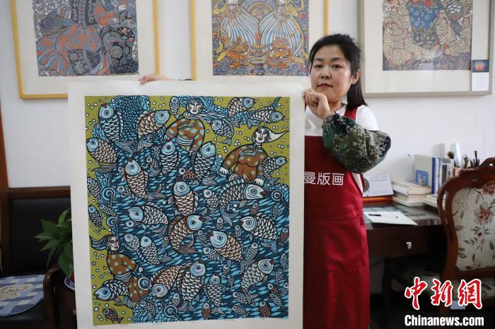 圖為王秀春展示版畫作品?！埩只?攝