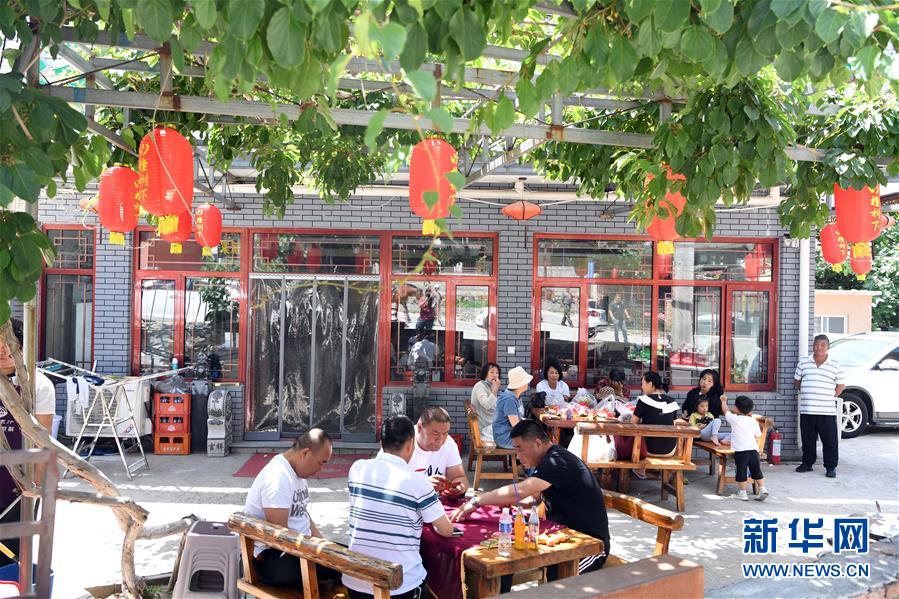 6月4日，游客在天津市薊州區(qū)下營鎮(zhèn)常州村農(nóng)家院休閑。 天津市薊州區(qū)下營鎮(zhèn)常州村村民以生態(tài)文明為理念，集資打造“歐式小鎮(zhèn)”，目前當?shù)孛磕杲哟慰?5萬多人，旅游綜合收入1.2億元，其中農(nóng)家院收入8100多萬元，走出了休閑農(nóng)業(yè)與鄉(xiāng)村旅游產(chǎn)業(yè)結(jié)合的鄉(xiāng)村振興之路。 新華社記者 馬平 攝